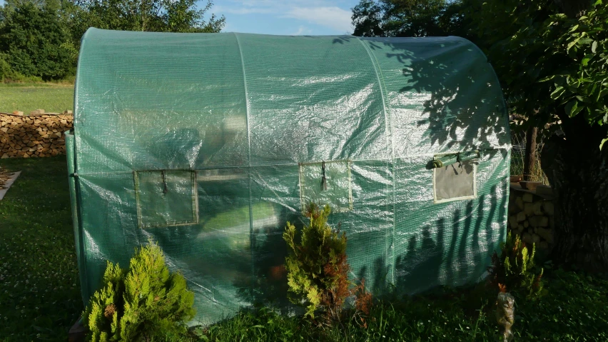 a green house in the middle of a field covered with plastic