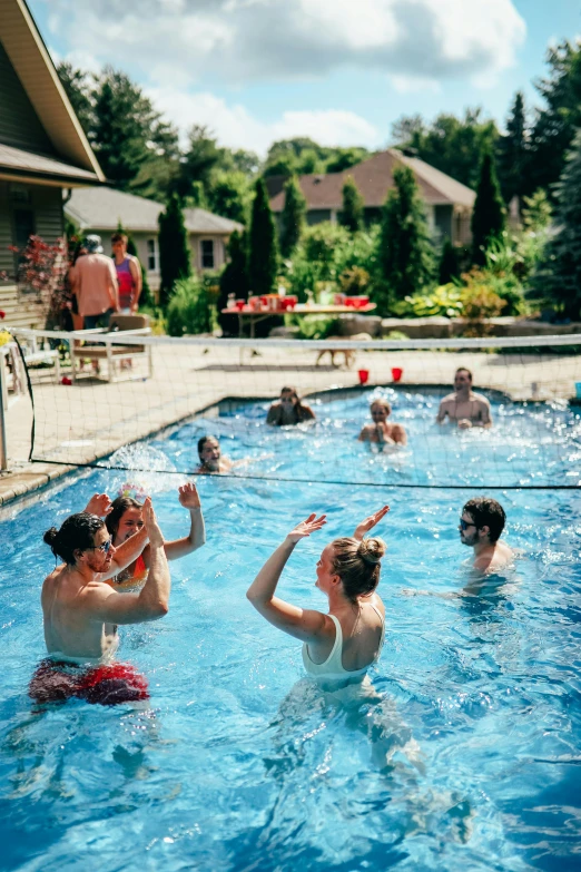 many people enjoying in the pool near some houses