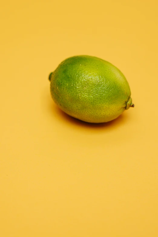 a mango fruit sits on an yellow surface