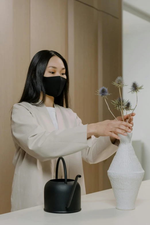 a young woman arranging some fake flowers in a vase