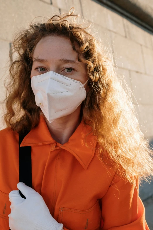 a woman in an orange shirt wearing a face mask and gloves