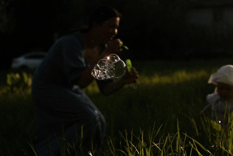 a woman and her toddler blowing bubbles in a field