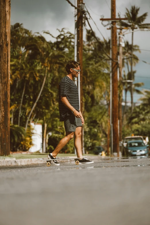 man skateboarding down the street under some palm trees