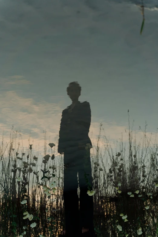 a man standing next to a field with a sky in the background