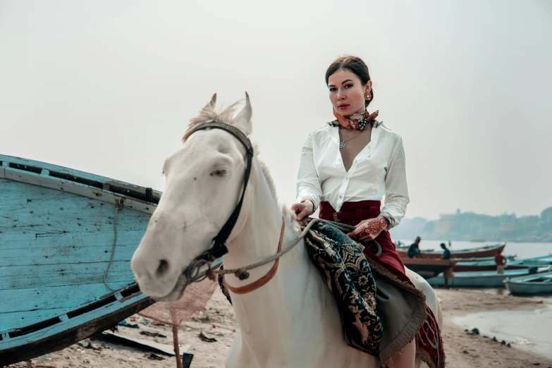a woman sits on a white horse near boats