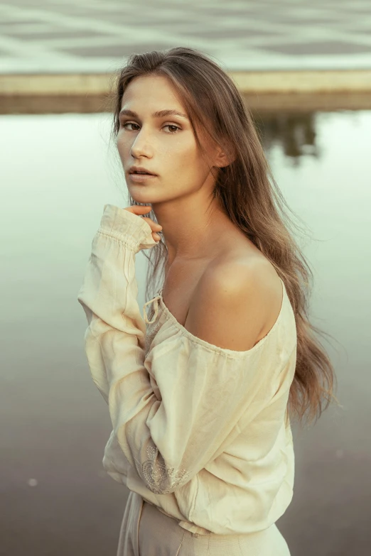 a beautiful woman posing for a portrait in front of a lake
