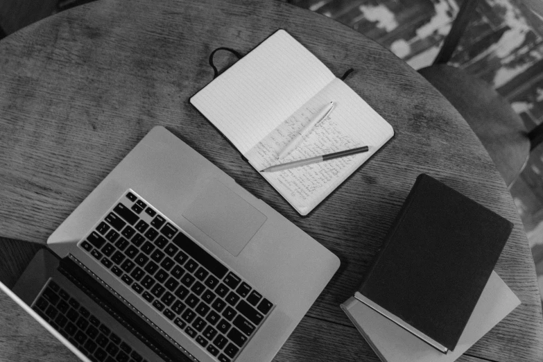 laptop, notebook and paper on table with papers