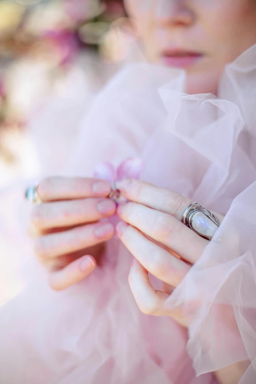 a girl is wearing rings and holding a dress