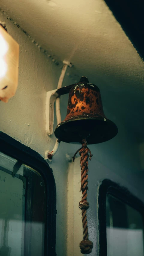 a bell hangs from the ceiling in front of a mirror