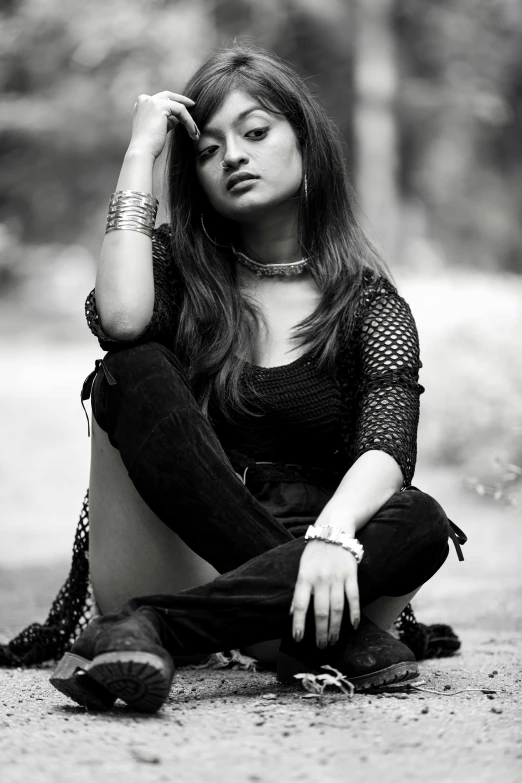 a young woman sitting on the ground with her hands in her hair