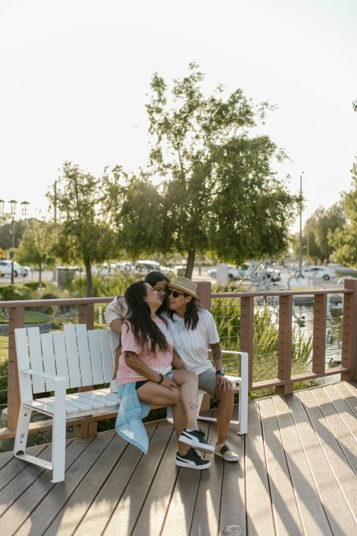 two women kiss on the back of a wooden bench