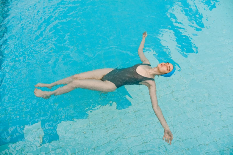 a woman in black bathing suit floating in a pool