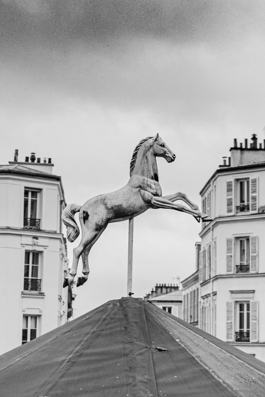 a horse statue atop of a building near a street