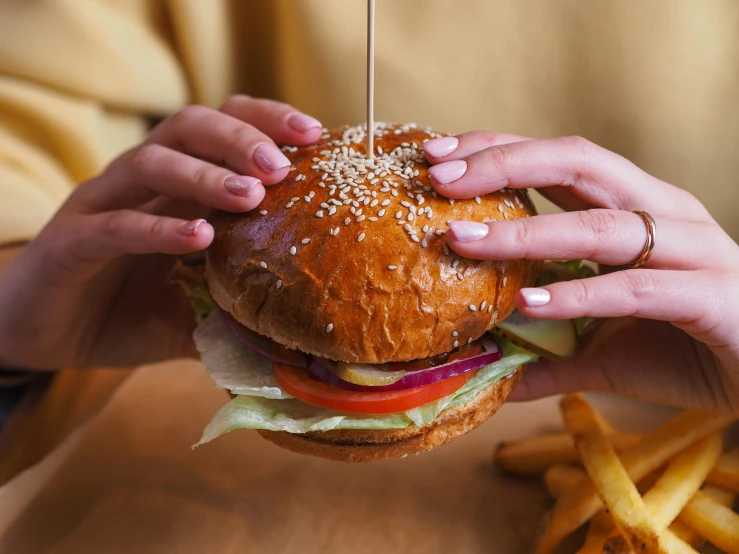 the person is holding up a burger and french fries