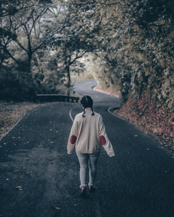 a young woman is walking along a road