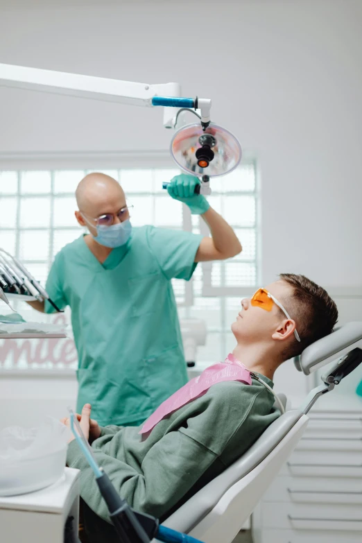 a dentist in the hospital with a man on a chair and other doctors