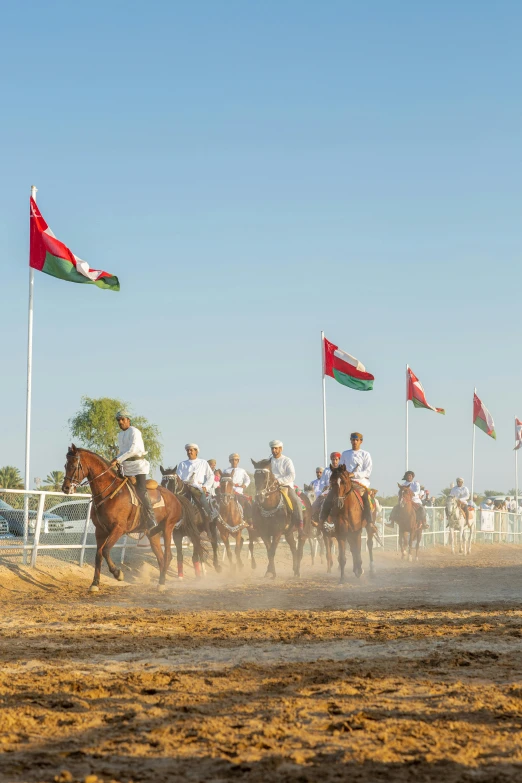 a bunch of people riding horses by some flags