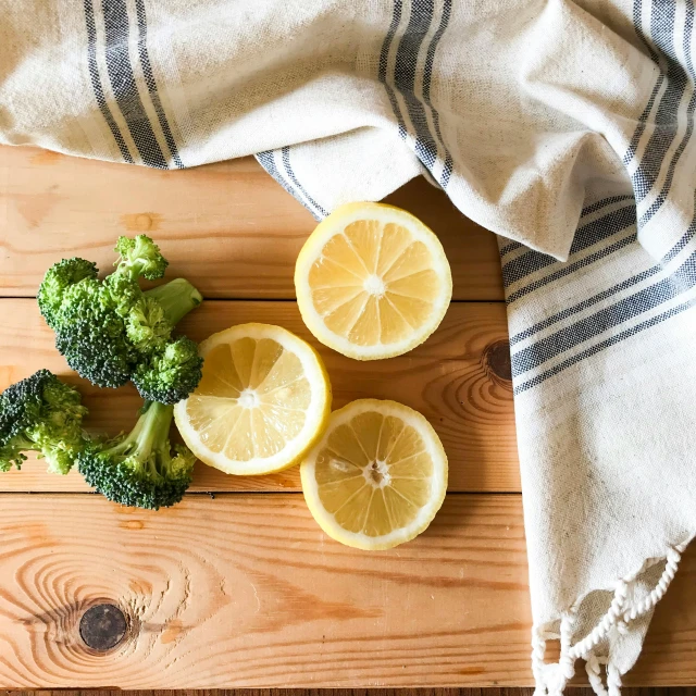 broccoli and lemon slices sit on a  board