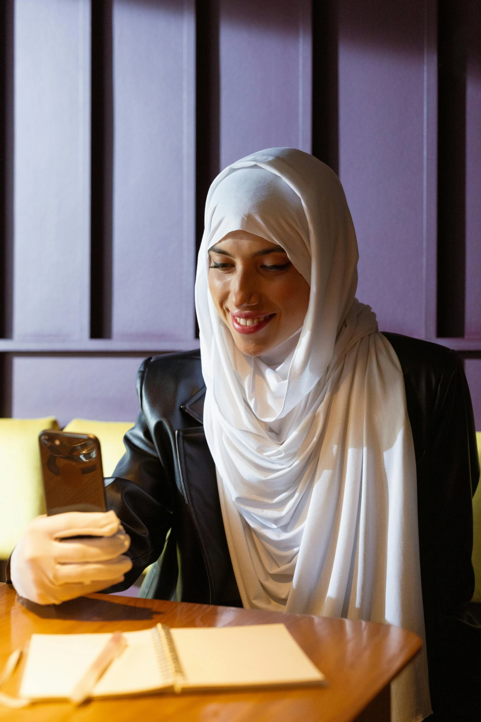 a young woman sitting at a table with a phone