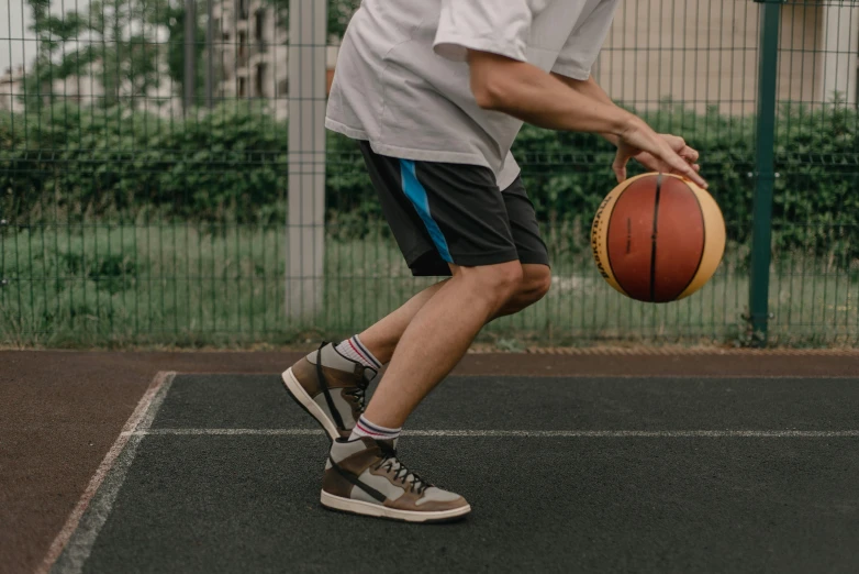 a man with a basketball on his foot stands near a gate