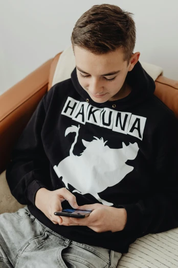 a boy sitting on a chair while looking at his cell phone