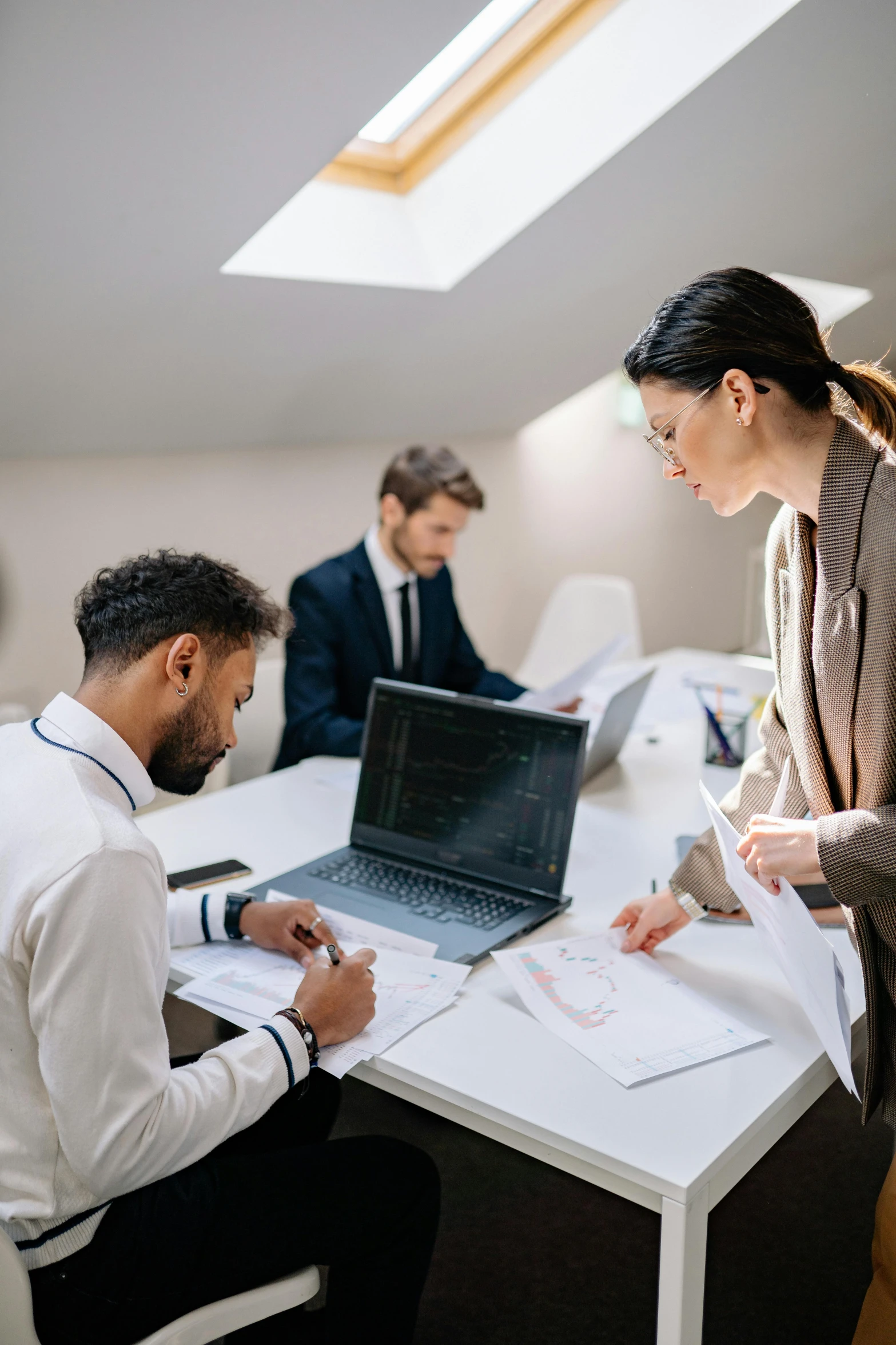 two people sit at a desk with papers and a laptop on it