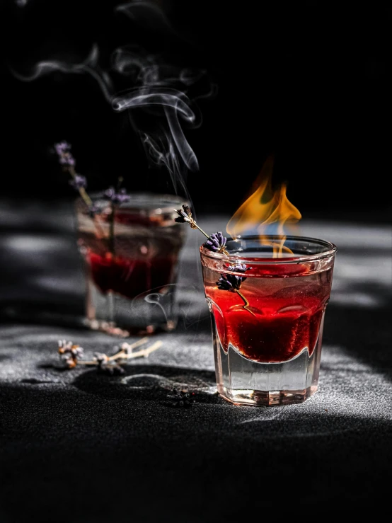 two smokes rise from a cocktail glass with liquor