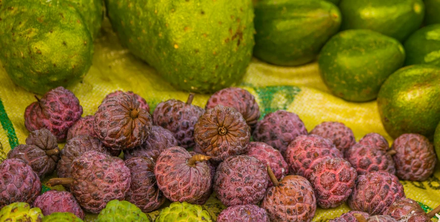 green and pink fruits on a table next to bananas