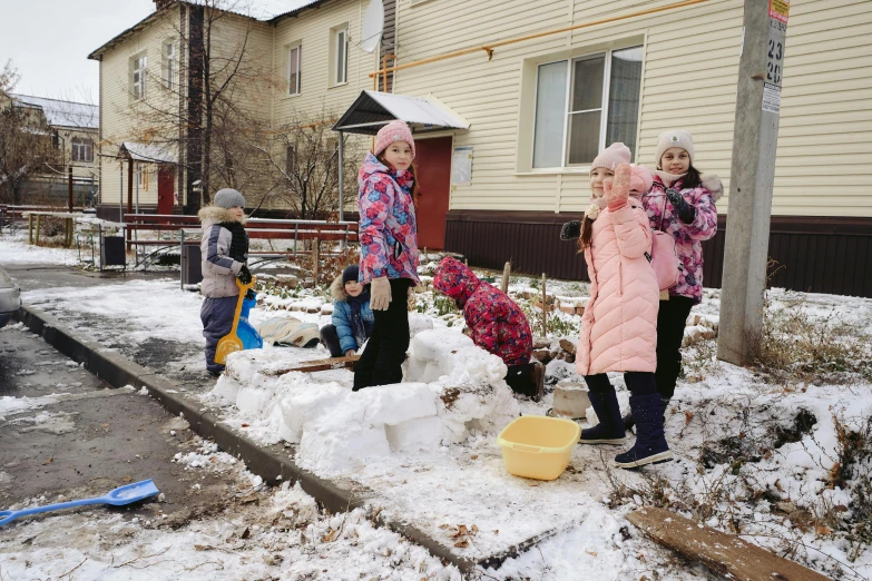 four children cleaning up their lawn in the snow