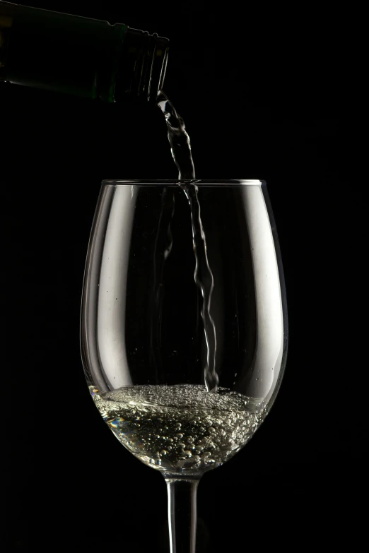 a wine glass filled with water being poured