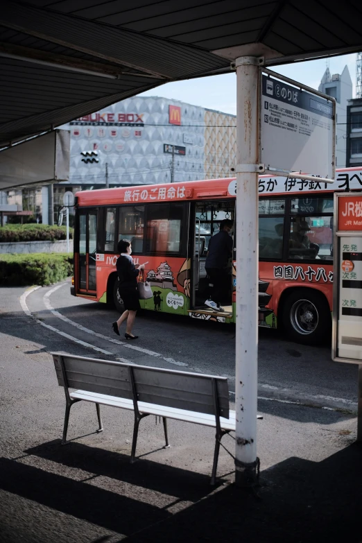 an orange and white bus parked near a bus stop