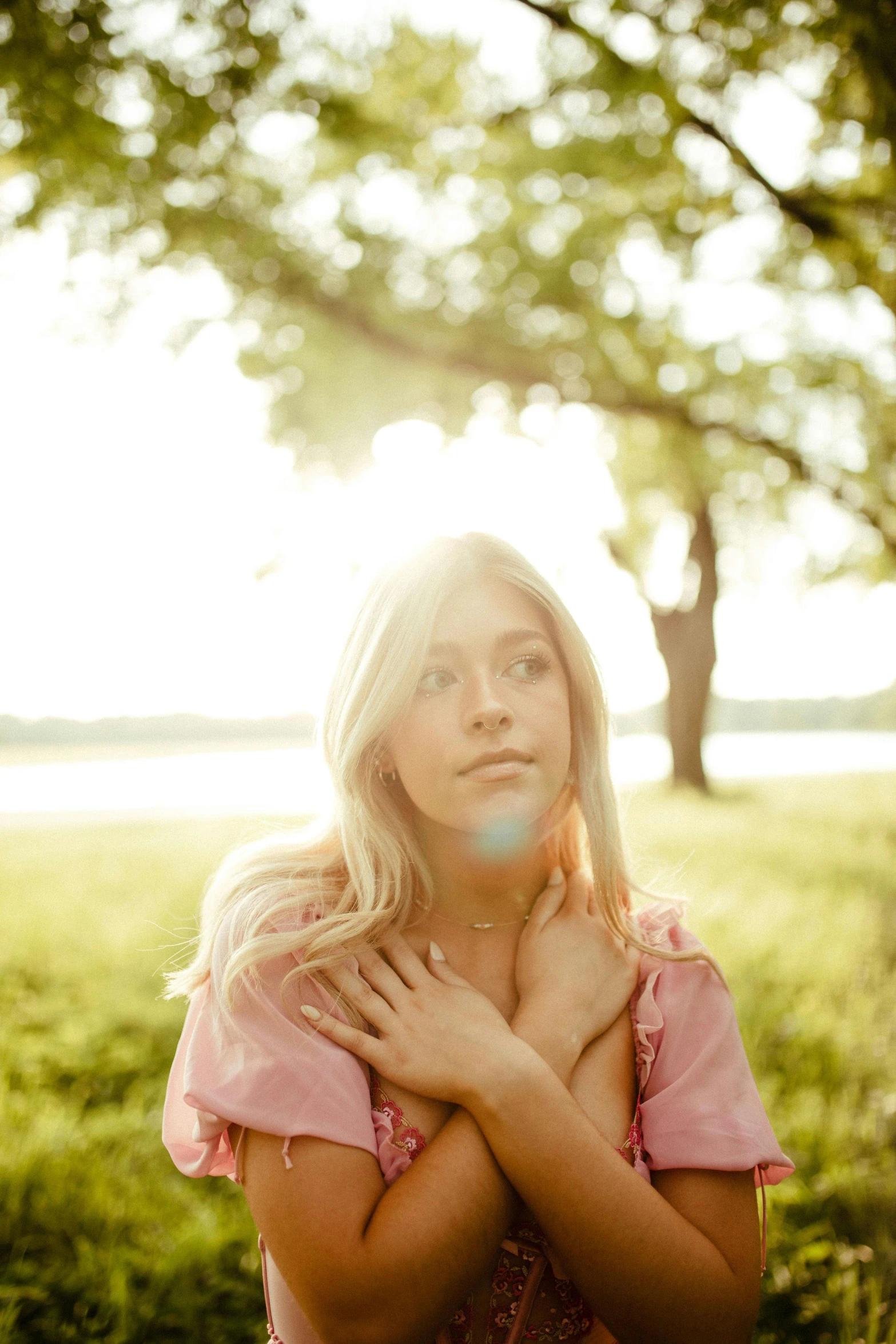 a beautiful blonde standing in the grass near a tree