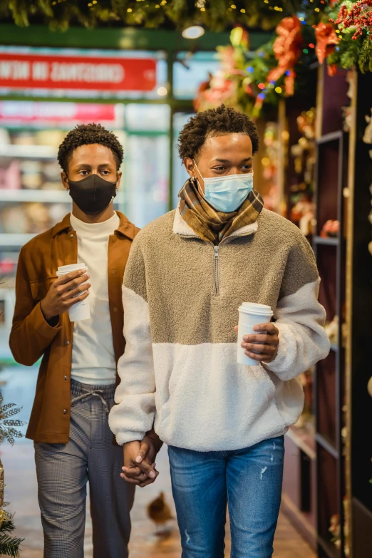 two people in masks walking down a street holding hands