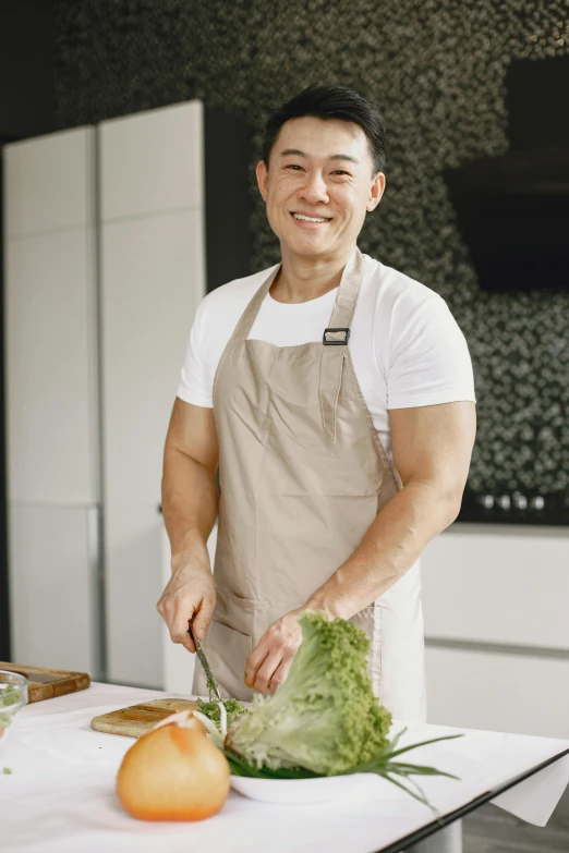 a man in white shirt and brown apron  up vegetables