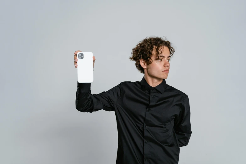 a young man with curly hair holding up a cell phone