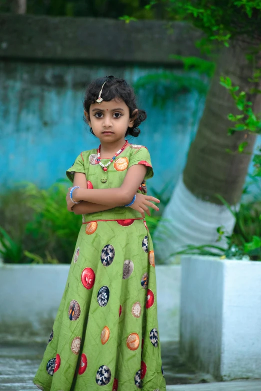 a  stands with her arms folded near a wall