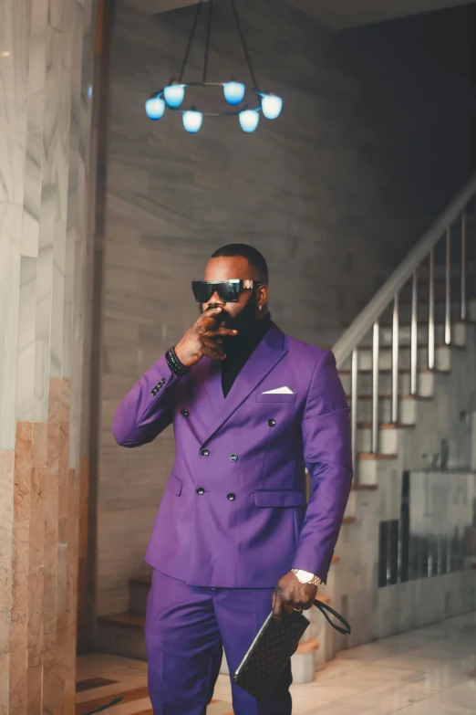 a man in a purple suit and sunglasses holding a black purse