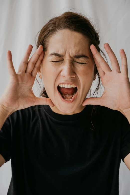 a girl is laughing and holding her hands up in front of her face