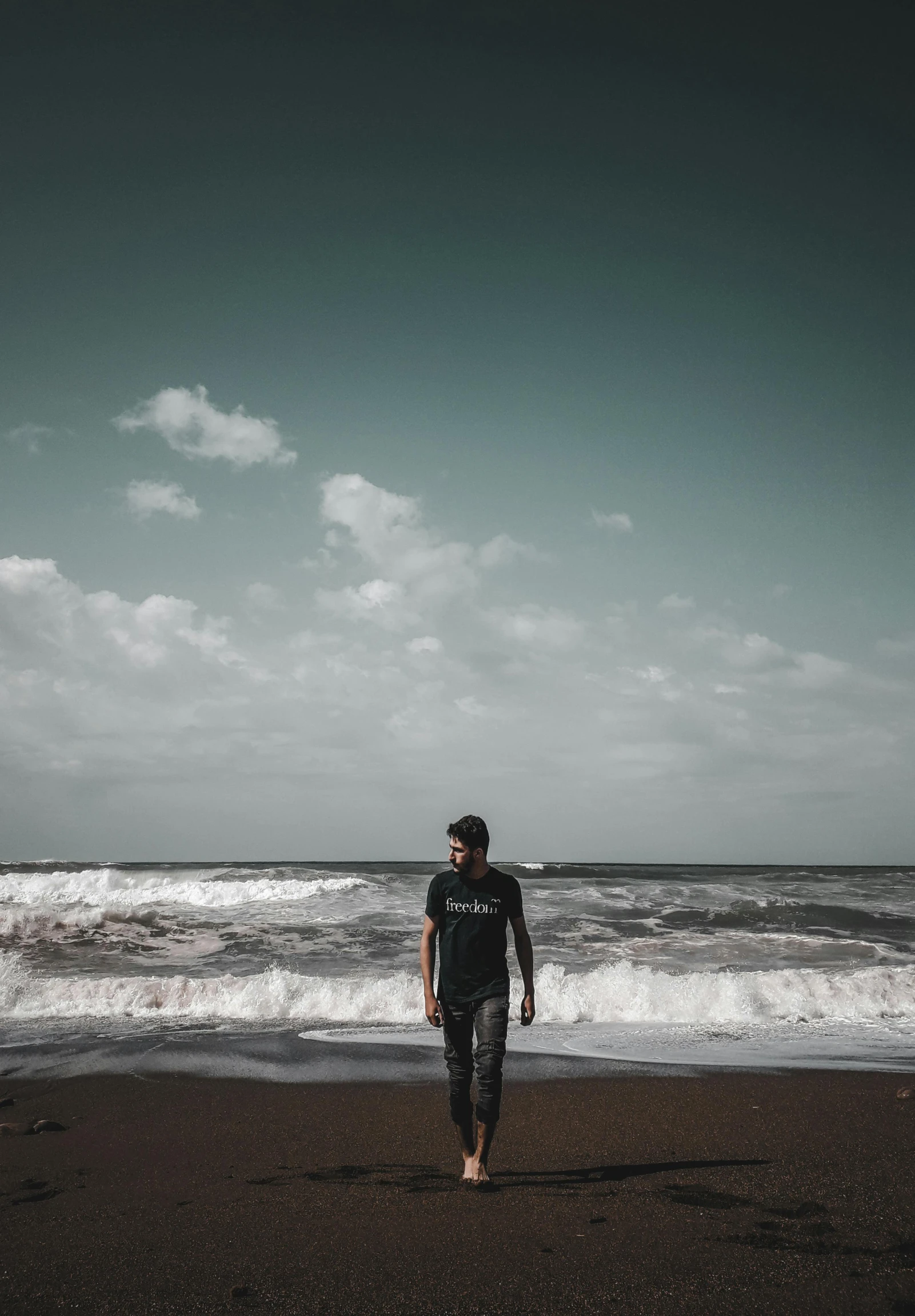 a surfer standing on the beach in front of a body of water