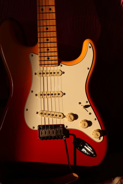 a red and yellow guitar sitting on a table