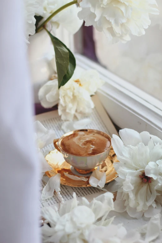 a cup and saucer with saucer sits on a saucer in front of flowers