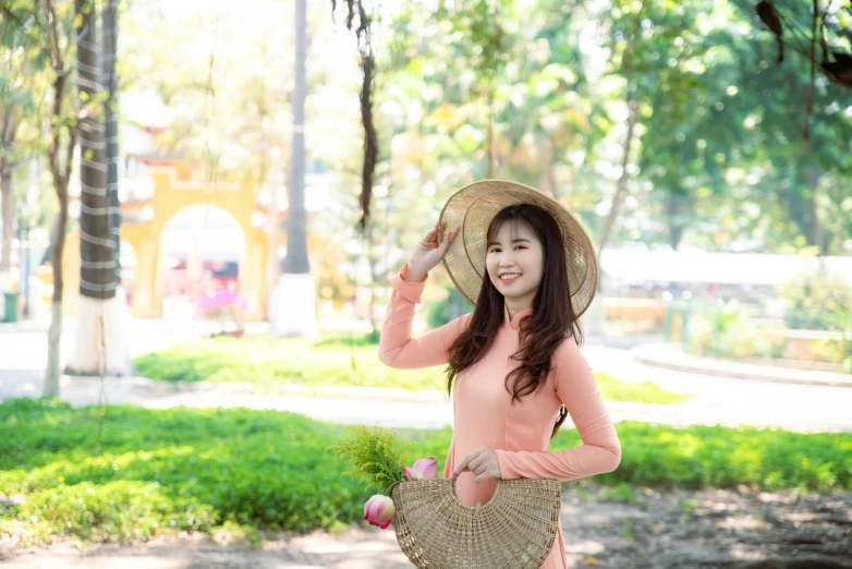 a girl wearing a straw hat holds flowers