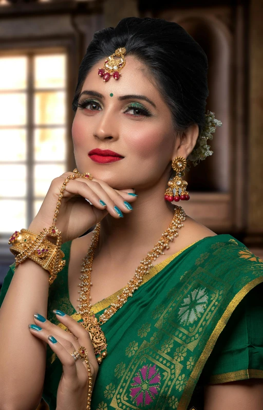 the woman in the green sari is wearing many jewelry pieces