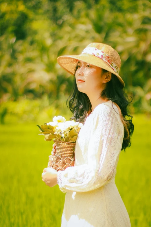 woman in a hat holding a basket of flowers and wearing white dress