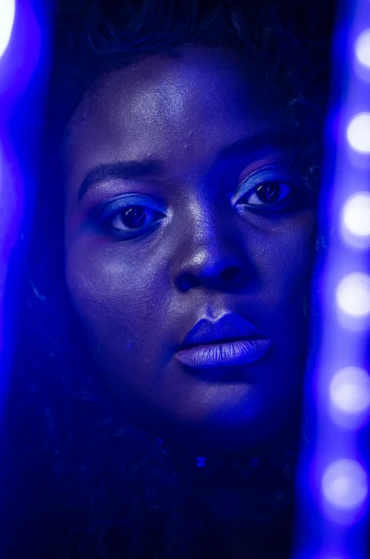 a black woman with bright blue eyes is looking into the mirror