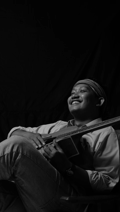 a man playing a guitar sitting on a chair