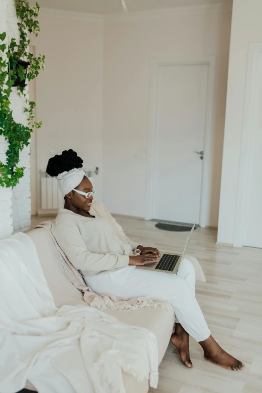 woman using laptop on white couch in room