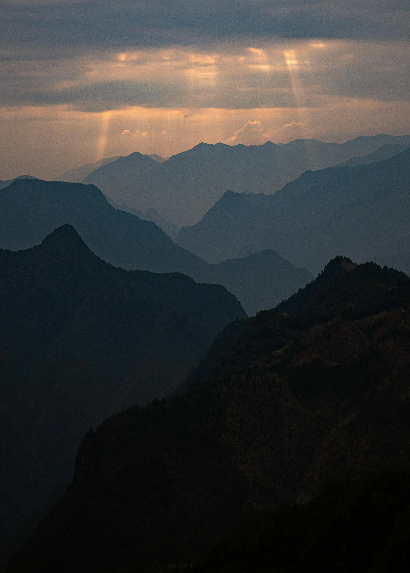 the sun breaks through the clouds on top of the mountains