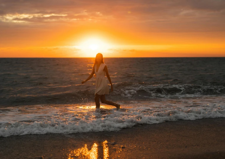 a woman in the surf at sunset is dancing