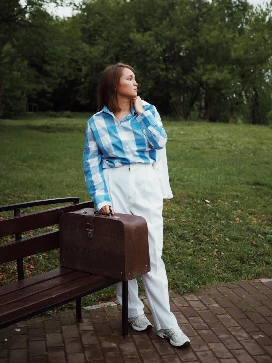 a woman sitting on a park bench holding a brown briefcase